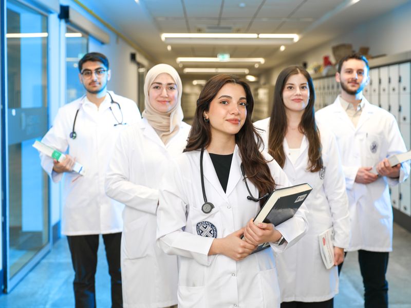 A diverse group of medical trainees in white coats